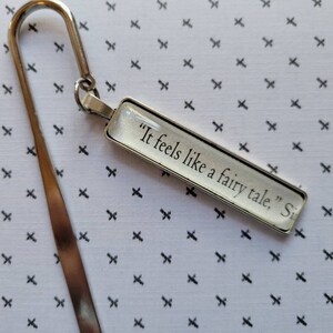 May include: Silver bookmark with a glass charm that says "It feels like a fairy tale, Si".