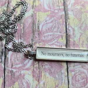 Collar con colgante rectangular No Mourners No Funerals hecho con páginas del libro Six of Crows