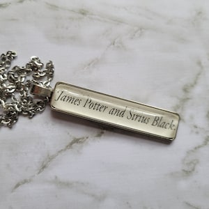 May include: A silver chain necklace with a rectangular pendant that reads "James Potter and Sirius Black."