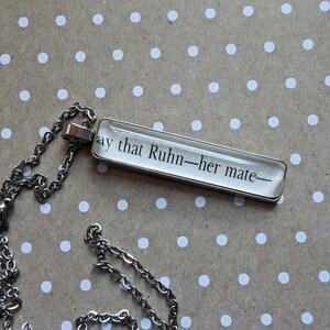 Puede incluir: Un collar de cadena de plata con un colgante rectangular que dice "Say that Ruhln - her mate - "