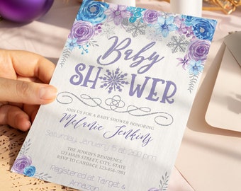Op de afbeelding: Een baby shower uitnodiging met een aquarel bloemenontwerp in tinten paars en blauw. De uitnodiging bevat een sneeuwvlok en de tekst "Baby Shower" in een zilveren glitterlettertype. De tekst "Melanie Jenkins" is geschreven in cursief schrift. De uitnodiging bevat ook de datum, tijd en locatie van de douche, evenals de registratie-informatie.
