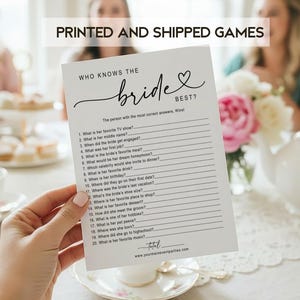 May include: A white card with the text "WHO KNOWS THE bride BEST?" is held in front of a table setting. The card has a list of questions. The words "PRINTED AND SHIPPED GAMES" are at the top of the image.