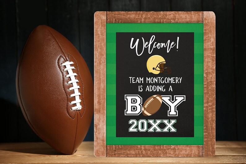 May include: A chalkboard sign with a green and white striped border announcing a baby boy. The sign reads "Welcome! Team Montgomery is adding a boy 20XX". A football helmet and football are illustrated on the sign.