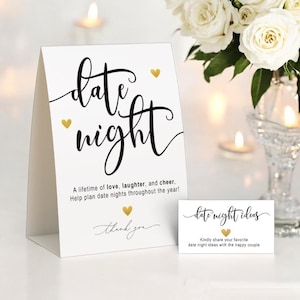 May include: A white card with the words "date night" in elegant black script, accented with gold hearts. The card includes the text "A lifetime of love, laughter, and cheer." A smaller card reads "date night ideas."