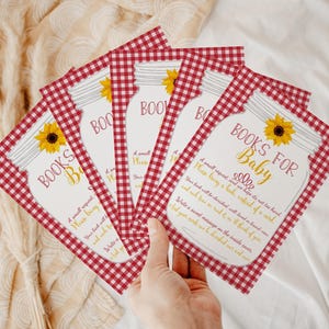 May include: Red and white gingham patterned cards with a mason jar illustration and the text "Books for Baby". The cards have a sunflower design and the text "A small request and we hope it's not too hard. Please bring a book, instead of a card."