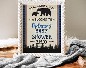 Puede incluir: Un cartel blanco con borde de cuadros azules y marrones. El cartel dice "Let the adventure begin" con una silueta de oso negro y cachorro. El texto continúa "Welcome to Melanie's Baby Shower 2.15.XX".