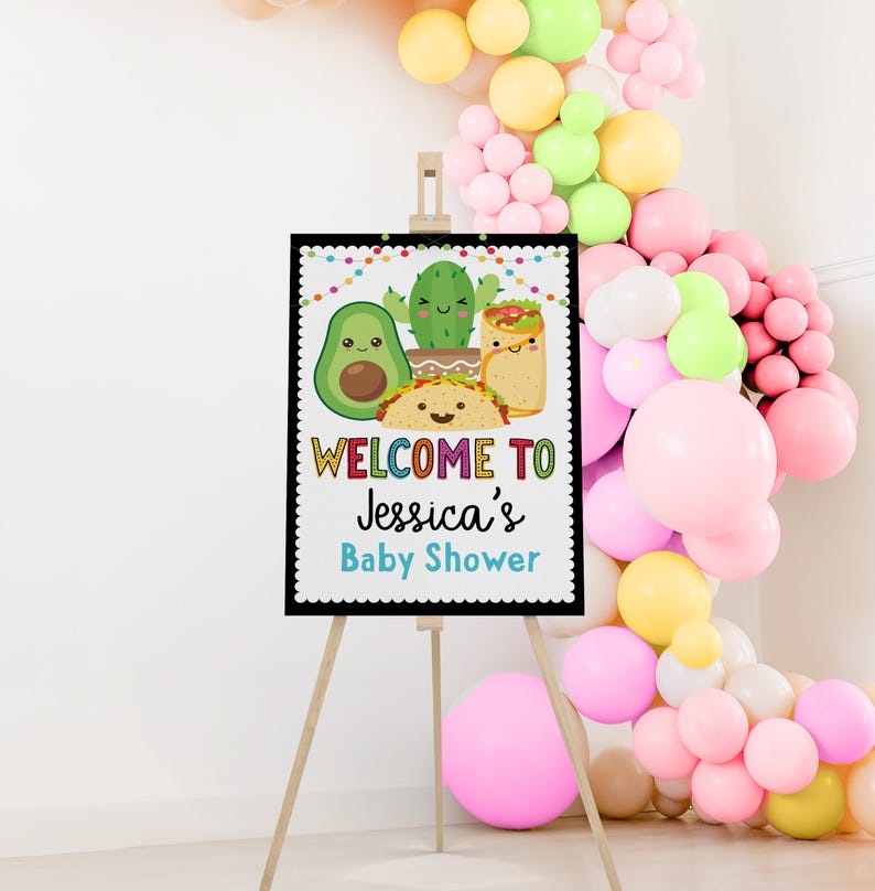 May include: Welcome to Jessica's Baby Shower sign with a black background and colorful text. The sign features a cartoon avocado, cactus, and taco with a burrito.
