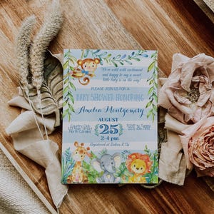 May include: A blue and white baby shower invitation with a jungle theme. The invitation features a monkey, giraffe, elephant, and lion. The text on the invitation reads "We're wild with excitement and happy to say a sweet little baby is on the way! Please join us for a baby shower honoring Amelia Montgomery. August 25, 2-4 pm. Country Club, 123 Main Street, North Carolina. Registered at Babies R Us."