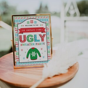 May include: A gold-framed sign with a white background and colorful Christmas sweater patterns. The sign reads "Welcome to the Johnson Family Ugly Sweater Party".