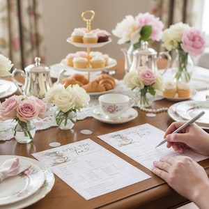 Op de afbeelding: Een theefeestje met bloemstukken, cupcakes en gebak. Zilveren theepotten, kopjes en borden zijn op een houten tafel geplaatst. Twee vellen papier met de tekst "Spill the Tea" liggen op de tafel.