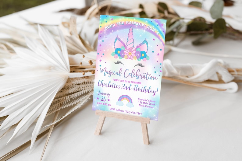 May include: A rainbow-themed invitation for a child's 2nd birthday party. The invitation features a unicorn with a rainbow and stars. The text reads "Over the Rainbow for a Magical Celebration Charlotte's 2nd Birthday!" with the date and time of the party.
