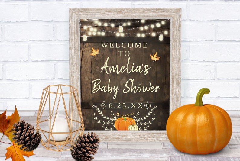 May include: A rustic wooden sign with a welcome to Amelia's Baby Shower message, featuring string lights, fall leaves, and pumpkins. The date 6.25.XX is also included.