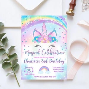 May include: A rainbow-themed invitation for a child's 2nd birthday party. The invitation features a unicorn with a sparkly horn and a flower crown. The text reads "Over the Rainbow for a Magical Celebration Charlotte's 2nd Birthday!" with the date, time, and RSVP information.