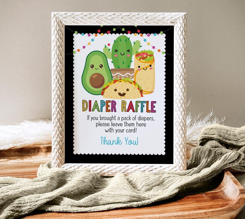 May include: A white frame with a black background and a colorful sign that says "Diaper Raffle". The sign has a cartoon image of a taco, avocado, cactus, and a burrito. The sign says "If you brought a pack of diapers, please leave them here with your card! Thank You!"