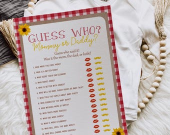May include: A baby shower game card with the text "Guess Who? Mommy or Daddy?" in red and yellow. The card has a red and white checkered border and sunflower accents. The game is held by a hand, with a white onesie in the background.