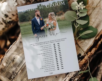 May include: A white wedding game card with the text "Bride or Groom" and "guess who". The card features a photo of a couple and a list of questions to guess who fits the description. The card is on a wooden surface.