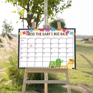 May include: A white calendar with a black border and colorful Mexican-themed decorations. The calendar is labeled "Guess the Baby's Due Date" and has numbers from 1 to 31. There are also images of avocados, cacti, and tacos.