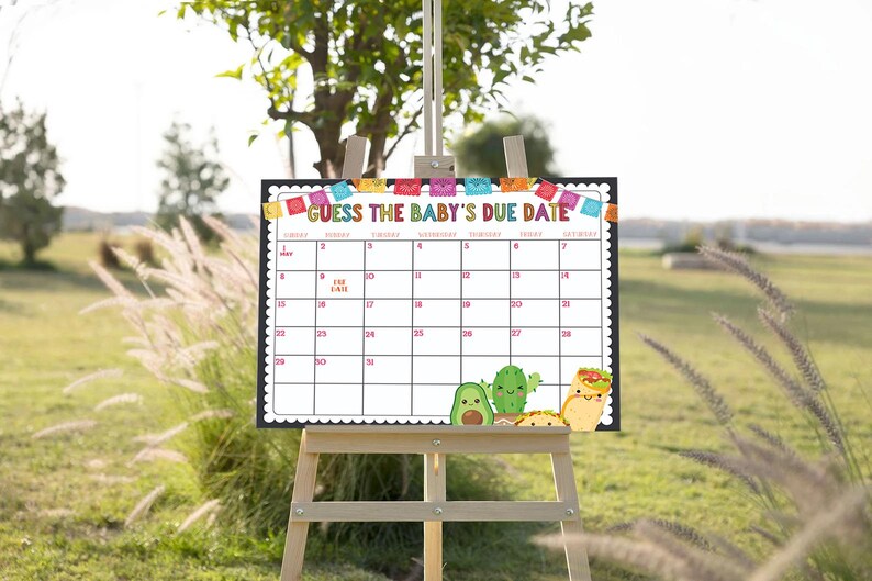 May include: A white calendar with a black border and colorful Mexican-themed decorations. The calendar is labeled "Guess the Baby's Due Date" and has numbers from 1 to 31. There are also images of avocados, cacti, and tacos.