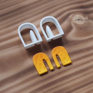 May include: Two white plastic cookie cutters shaped like arches, and two yellow and orange fondant arches with a geometric pattern.