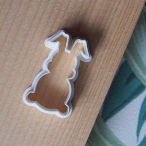 Op de afbeelding: Witte plastic koekjesvormer in de vorm van een konijn. De vormer heeft een eenvoudig ontwerp met afgeronde randen.
