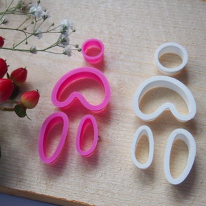 Könnte beinhalten: Zwei Sätze Ausstecher, einer rosa und einer weiß, in Form einer Person mit einem runden Kopf, zwei Armen und zwei Beinen.