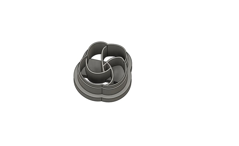 May include: A silver metal cookie cutter shaped like a four-leaf clover with a decorative design.