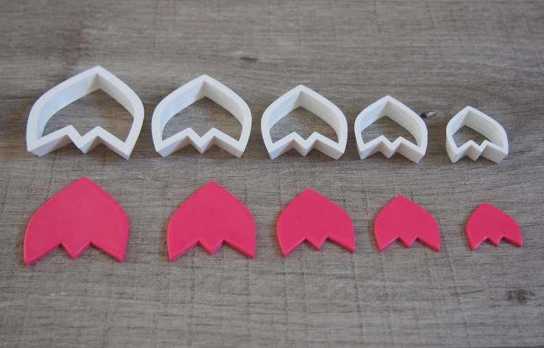 Peut inclure: Ensemble de six emporte-pi&egrave;ces &agrave; fleurs en plastique blanc et six formes de fleurs en p&acirc;te &agrave; sucre rose. Les emporte-pi&egrave;ces sont class&eacute;s par ordre d&eacute;croissant de taille de gauche &agrave; droite. Les formes en p&acirc;te &agrave; sucre sont dans le m&ecirc;me ordre en dessous des emporte-pi&egrave;ces.