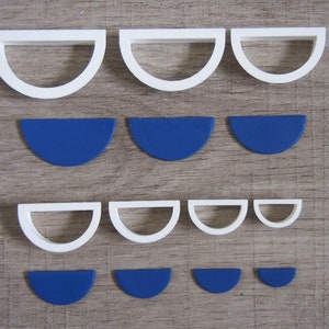 May include: Set of white plastic semi-circle cookie cutters with blue fondant semi-circles in various sizes.