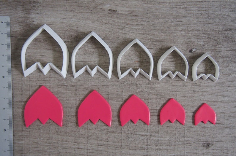 Peut inclure: Ensemble de six emporte-pi&egrave;ces en plastique blanc en forme de p&eacute;tale de fleur de diff&eacute;rentes tailles, avec six p&eacute;tales de fleur en p&acirc;te &agrave; sucre rose fabriqu&eacute;s avec les emporte-pi&egrave;ces.