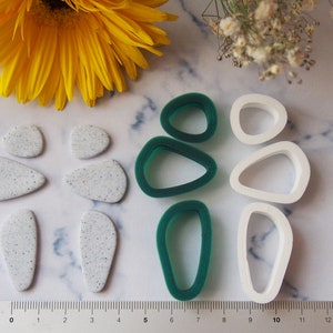 May include: A set of six polymer clay earring moulds. The moulds are in the shape of abstract teardrops. Three moulds are white and three are green.