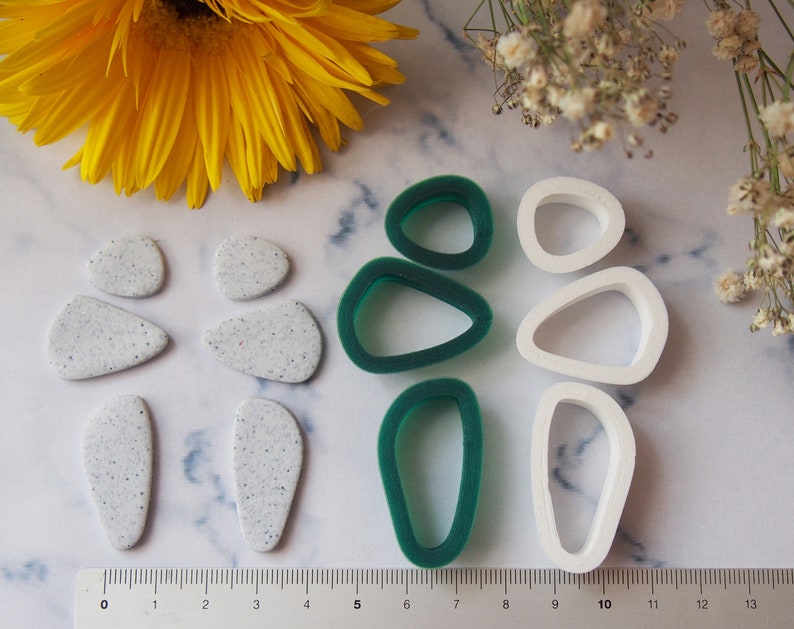 May include: A set of six polymer clay earring moulds. The moulds are in the shape of abstract teardrops. Three moulds are white and three are green.