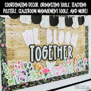 May include: A classroom bulletin board display featuring a wood-grain background, a floral border, and a banner with black and floral pennants. The text reads WE BLOOM TOGETHER in large letters, accented by colorful watercolor-style flower cutouts.