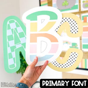 May include: Colorful ABC letters in a primary font style. The letters are in pastel colors, with the letter A in a green and white checkered pattern. The letter C has a yellow border with black polka dots. The text "PRIMARY FONT" is in a black rectangle.