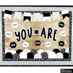 May include: Black and white classroom bulletin board with the words "YOU ARE" in large, bold letters. The board is decorated with black and white polka dot patterned borders, pennants, and half circles. There are also hexagonal shapes with positive affirmations such as "Brave", "Driven", "Unique", "Loved", "Talented", "Capable", "Enough", "Strong", "Kind".