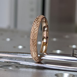 K&ouml;nnte beinhalten: Ein d&uuml;nner Goldring mit einem Blattmotiv, das um den gesamten Ring graviert ist.
