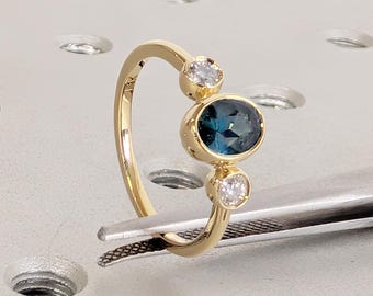 Anillo de compromiso de tres piedras con zafiro Montana engastado en bisel, oro amarillo de 14 quilates, zafiro azul verdoso ovalado, piedra de nacimiento de septiembre y diamante.