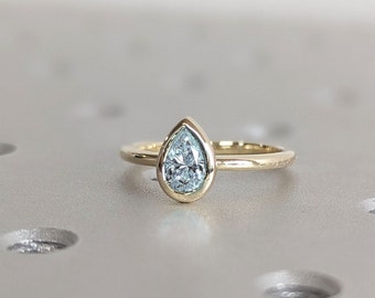 May include: A gold ring with a pear-shaped blue gemstone set in a bezel setting.