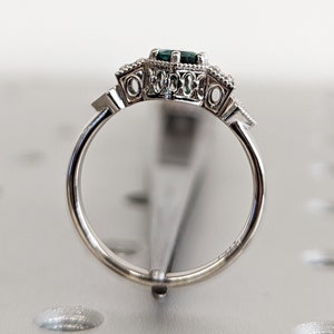 May include: A silver ring featuring a green gemstone set in an ornate filigree design.