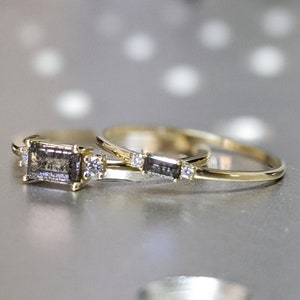 May include: Two gold rings with a grey rectangular stone and small diamonds on the band.