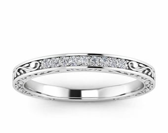 May include: A thin silver band with a delicate, ornate design and a row of small diamonds.