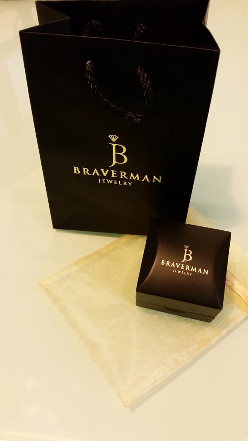 以下が含まれることがあります： 「Braverman Jewelry」と金色で書かれたロゴが付いた黒いギフトバッグと、「Braverman Jewelry」と金色で書かれたロゴが付いた小さな黒いジュエリーボックスです。