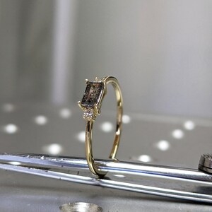 May include: A gold ring with a rectangular brown gemstone and small diamonds on the band.