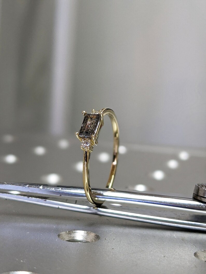 May include: A gold ring with a rectangular brown gemstone and small diamonds on the band.