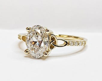 May include: A gold engagement ring with a large oval-shaped diamond set in a Celtic knot design. The band is accented with smaller diamonds.