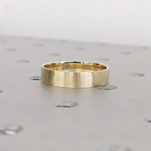 May include: A simple gold wedding band with a brushed finish.