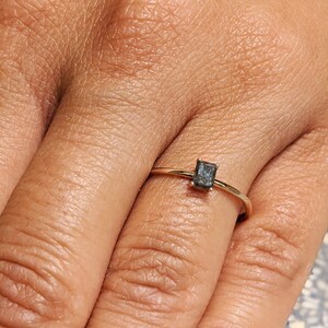 May include: A gold ring with a dark gray rectangular gemstone.