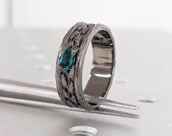 May include: A silver ring with a detailed design of leaves and a teal gemstone in the center.