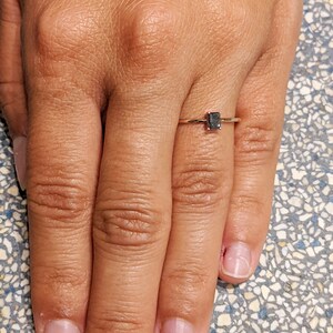May include: A simple gold band ring with a small, black, rectangular gemstone.