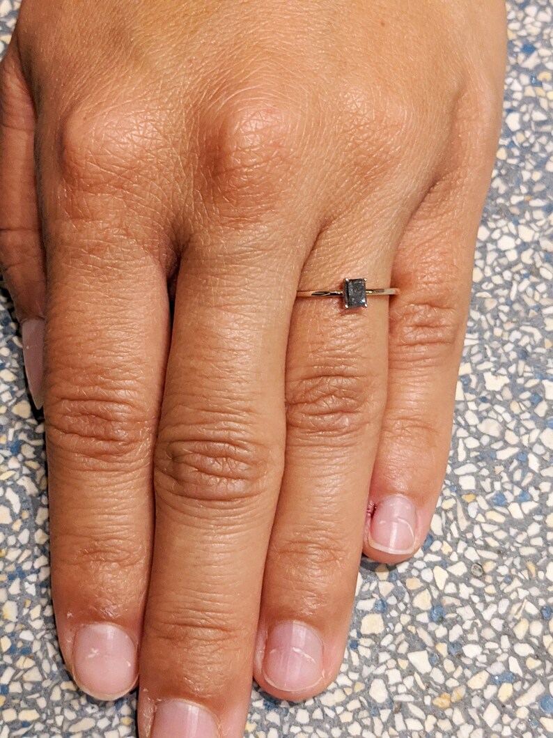 May include: A simple gold band ring with a small, black, rectangular gemstone.