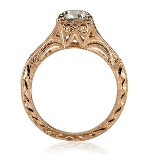 K&ouml;nnte beinhalten: Ein Verlobungsring aus Ros&eacute;gold mit einem runden Diamanten, der in einer filigranen Fassung sitzt. Die Ringschiene ist mit aufwendigen Gravuren verziert.